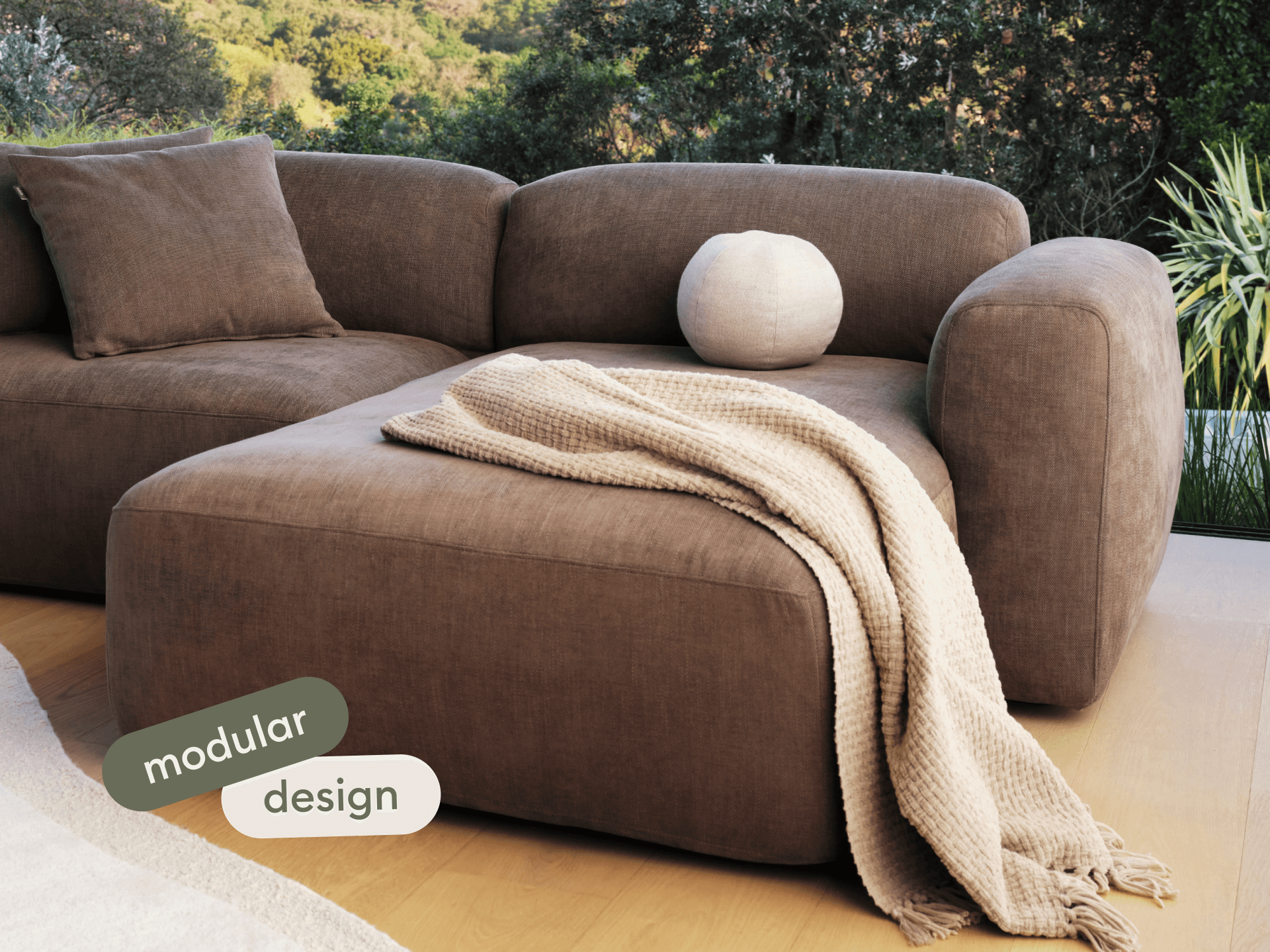 Luxurious brown modular sofa in premium fabric with plush cushions and a textured beige throw, set in a contemporary living room with natural light.