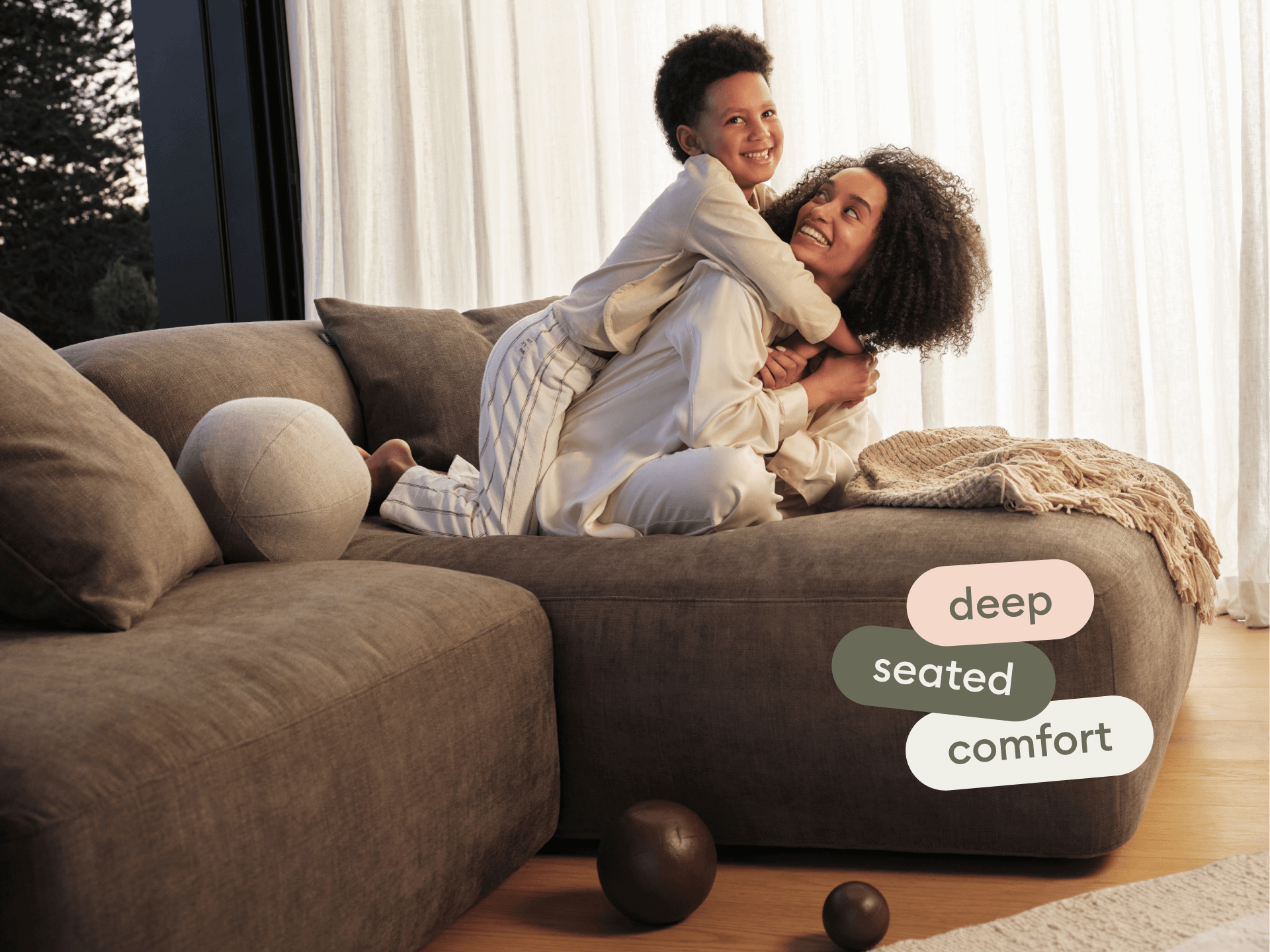 Luxurious sectional sofa in plush grey fabric, featuring deep seating and soft, rounded cushions. Set in a cosy living room with wooden flooring.
