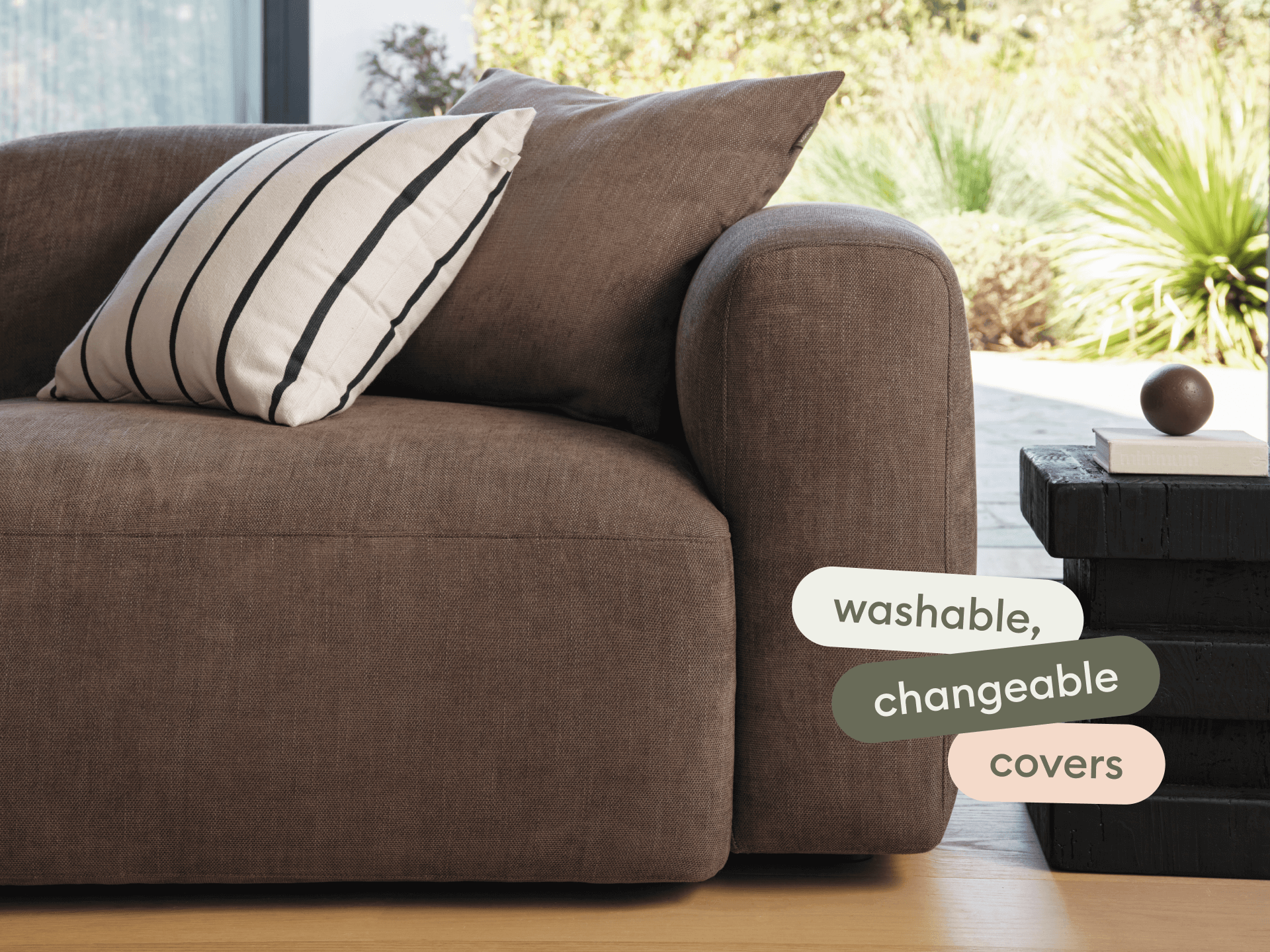 Luxurious brown linen sofa with plush, rounded arms and washable, changeable covers, set in a modern living room with natural light and a sleek coffee table.