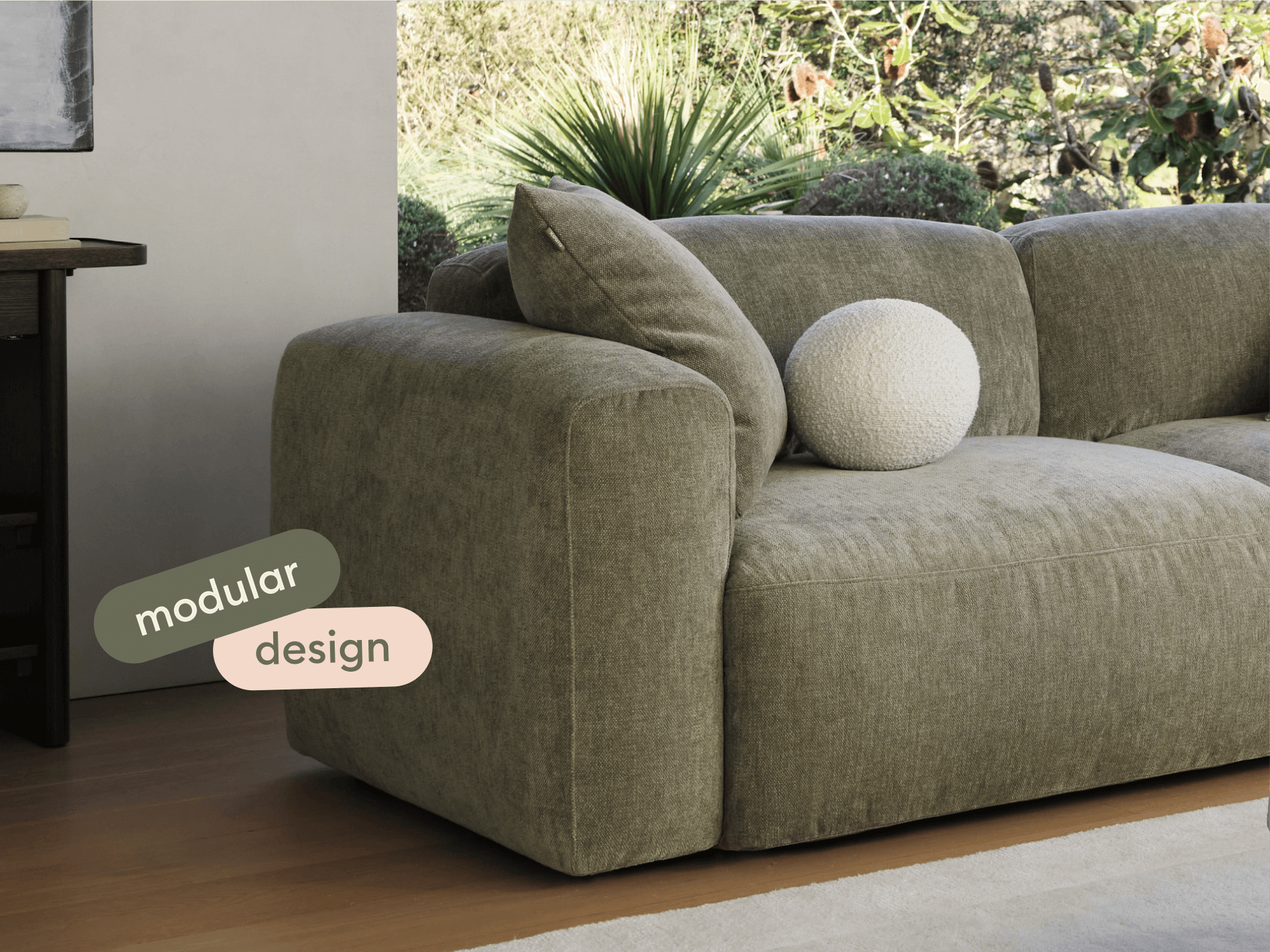Luxurious modular sofa with plush olive-green upholstery, featuring deep seats and a rounded cushion, set in a sunlit, modern living room.