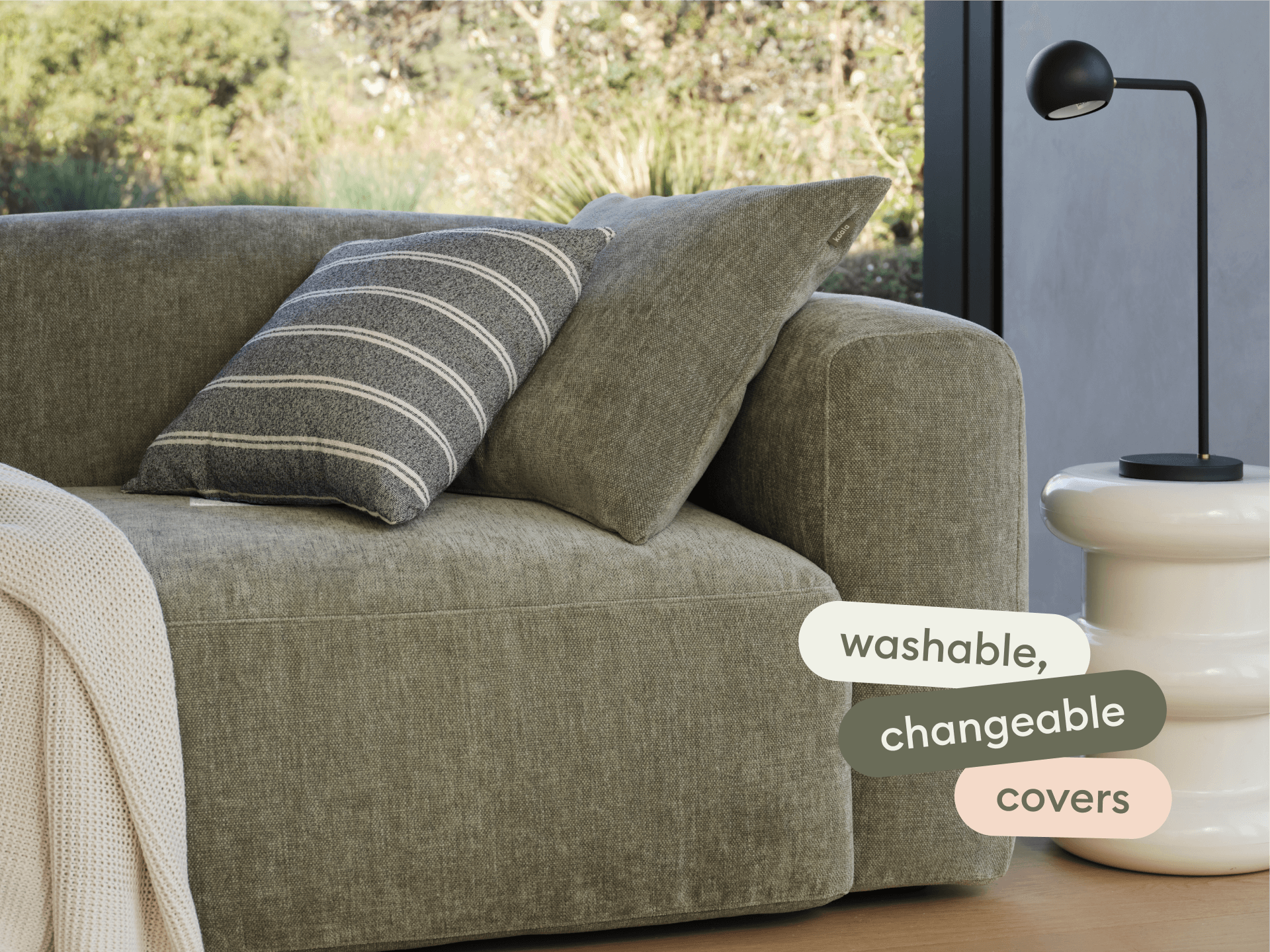 Luxurious olive-green sofa with washable, changeable covers. Features a plush, deep seat and striped cushion. Paired with a sleek white side table.