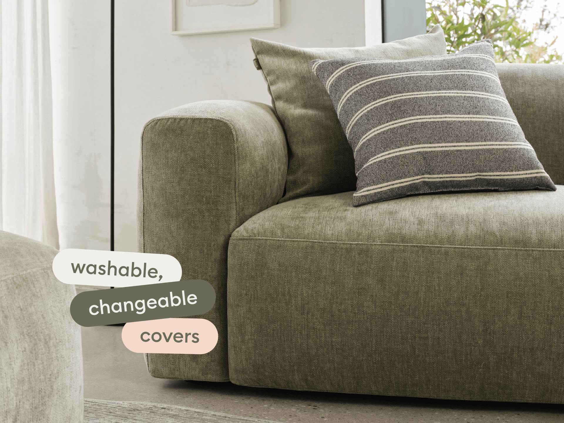 Luxurious olive green sectional sofa with plush, washable covers. Features robust upholstery and a striped cushion, set in a modern living area.