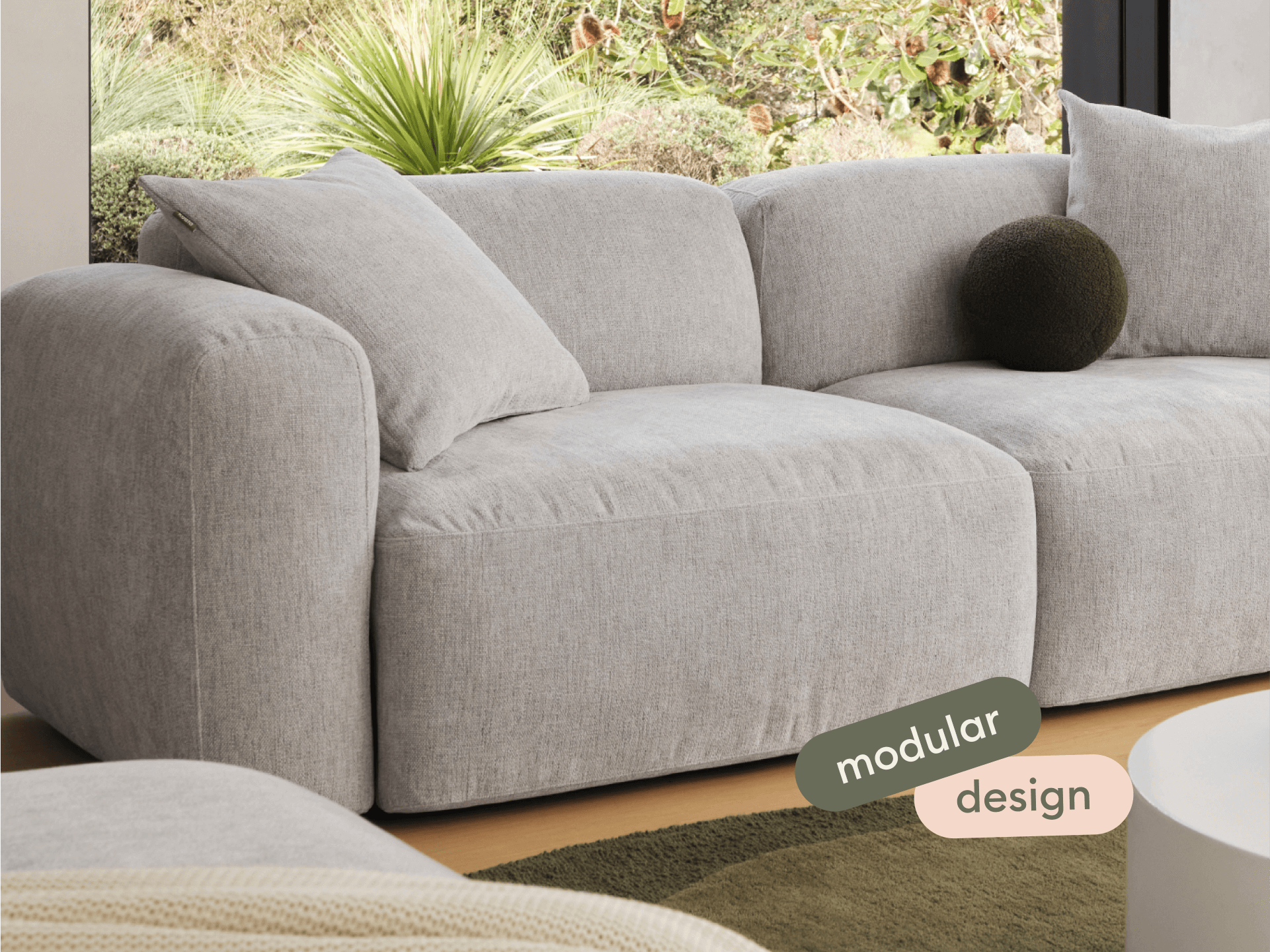 Luxurious grey upholstered modular sofa with plush cushioning, set in a contemporary living space. Soft curves and earthy tones enhance modern elegance.