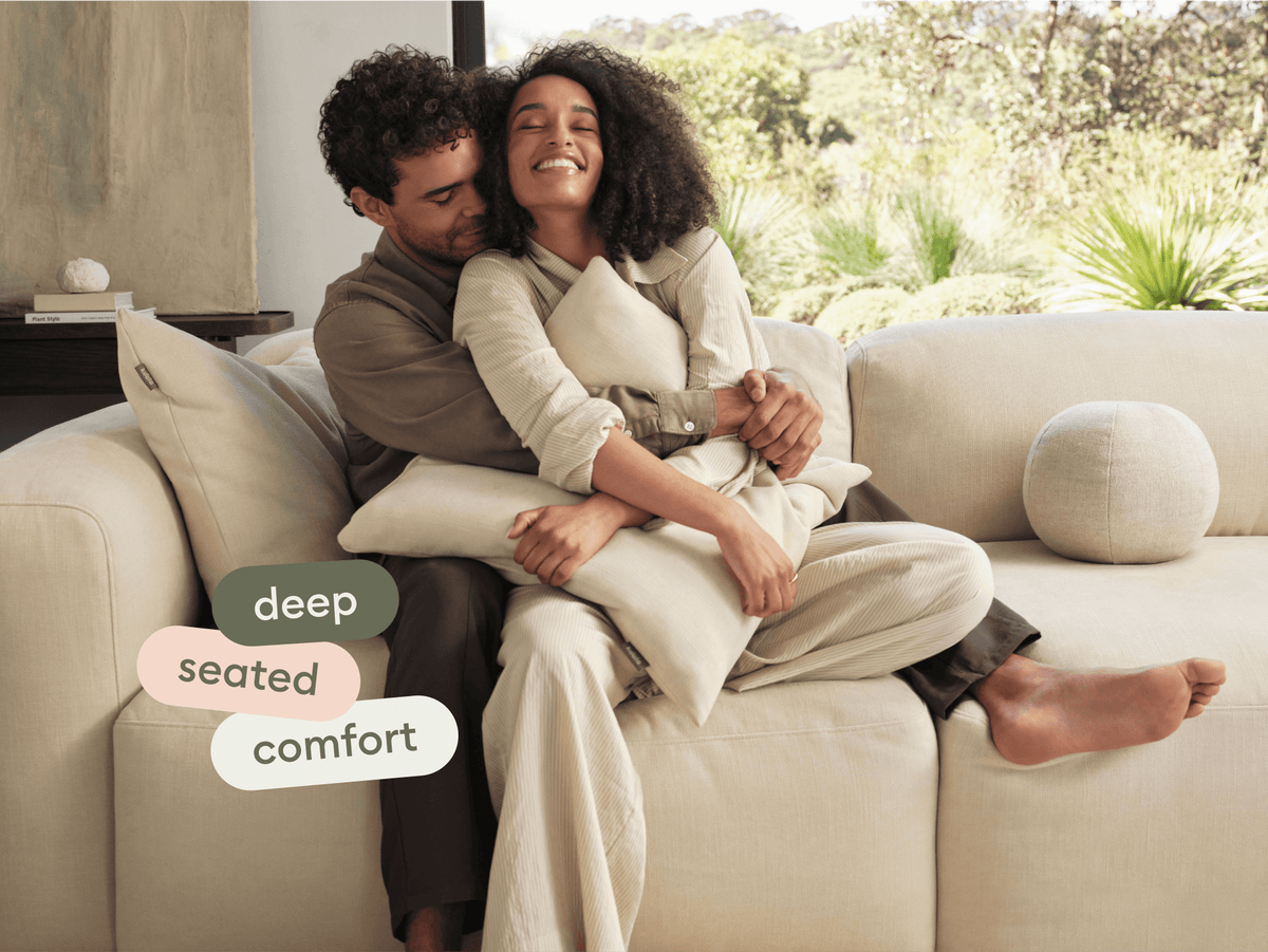 Luxurious beige sectional sofa with deep seating, plush fabric upholstery, and modern cushions in a bright living room overlooking a lush garden.