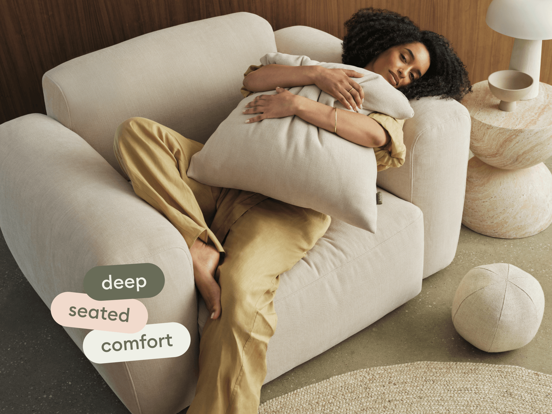 Luxurious cream sofa with deep seats, upholstered in soft fabric. Set in a chic living room with a neutral palette, complemented by a modern stone side table.