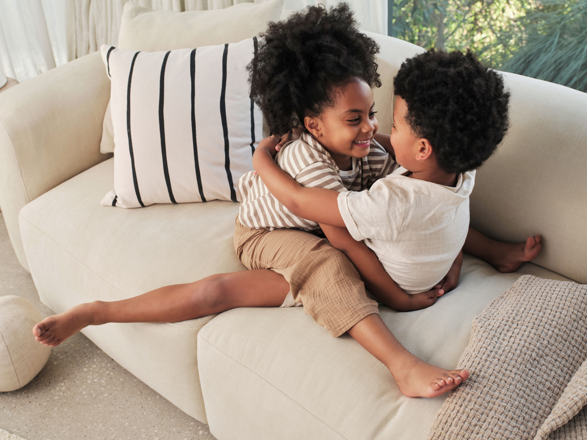 Luxurious cream-coloured sofa with plush cushions, textured upholstery, and sleek lines, set in a sunlit living room with large windows and natural decor.