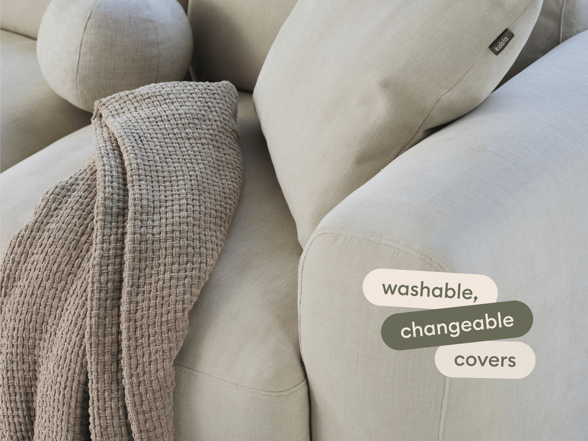 Beige modular sofa in linen blend with washable, changeable covers. Features plush cushions and waffle-textured throw, set in a modern living room.