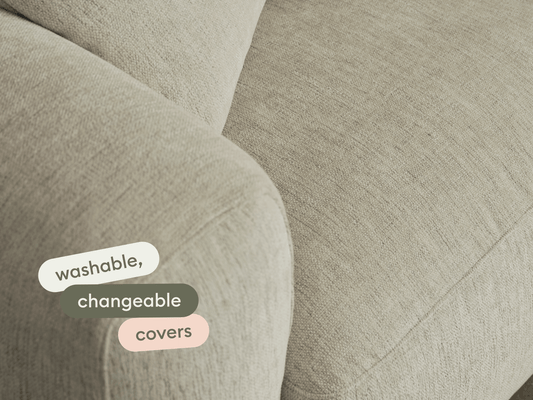 Modern beige fabric sofa with washable, changeable covers. Features soft, curved arms and a textured finish. Perfect for luxurious, versatile living spaces.
