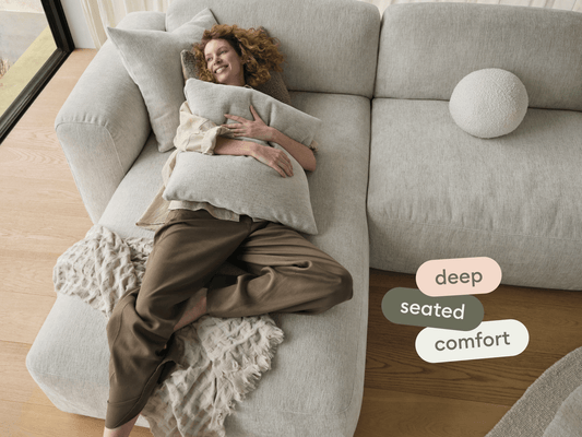 Luxurious light grey sectional sofa with plush fabric, deep seats, and sleek design. Set in a bright room with wooden floors, offering premium comfort.