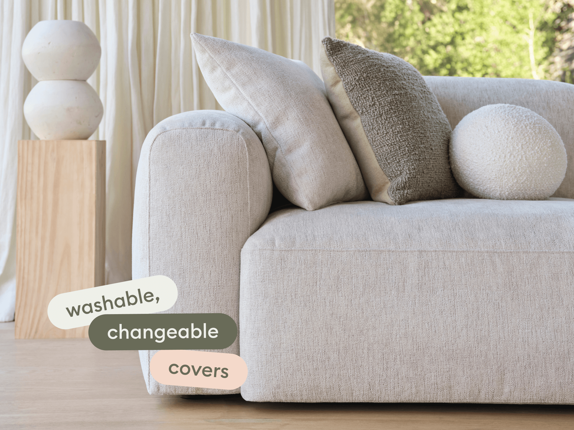 Luxurious light beige linen sofa with washable, changeable covers, featuring plush cushions. Set in a bright room with natural light and wooden accents.
