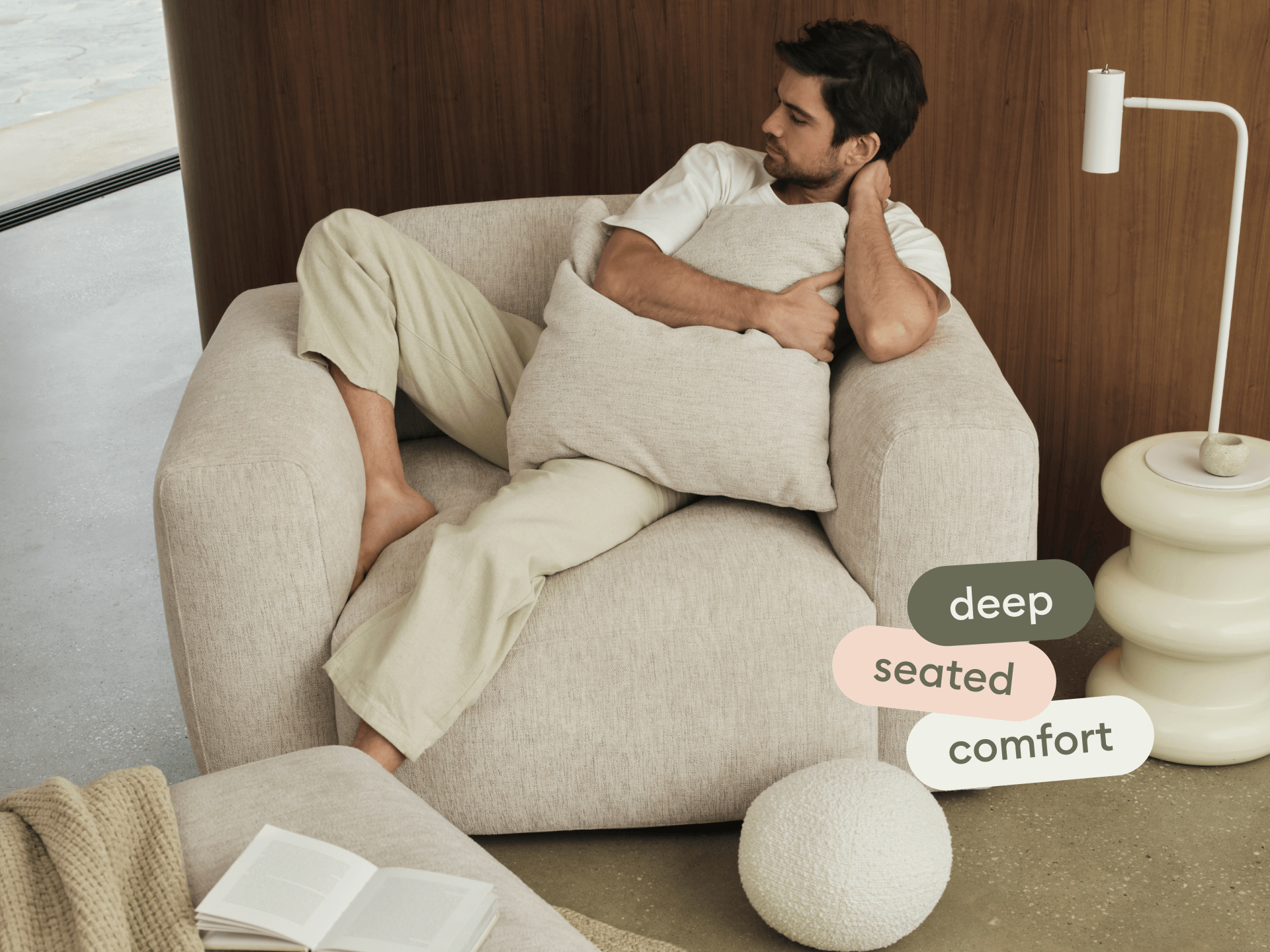 Modern beige armchair upholstered in soft, textured fabric. Features deep seat, plush cushions, and minimalist design. Set in a stylish, neutral-toned room.