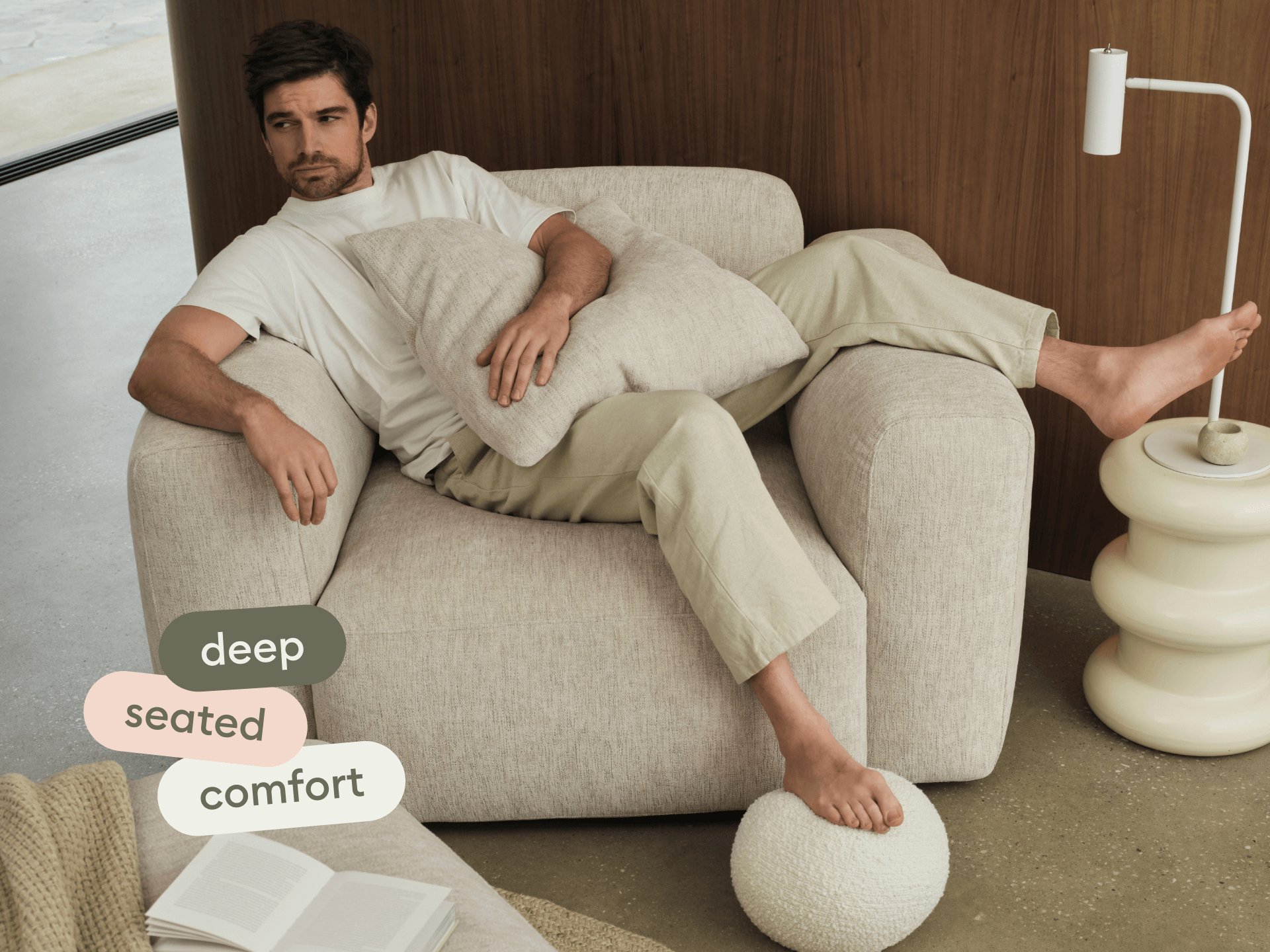 Luxurious, deep-seated armchair in soft beige upholstery, perfectly complementing a modern setting with a wooden backdrop and contemporary lighting.
