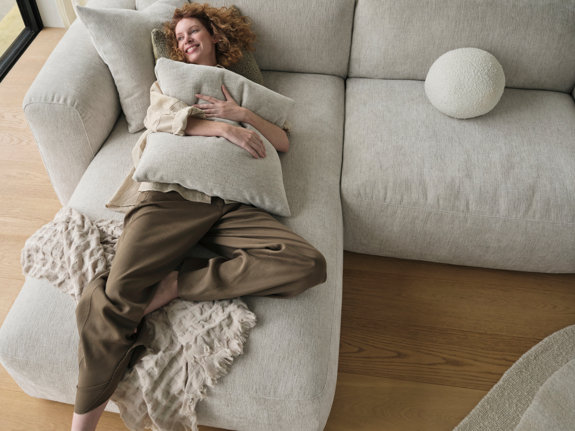 Luxurious modular sofa in soft grey upholstery, featuring deep cushions and sleek lines, set on warm timber flooring for a sophisticated living area.