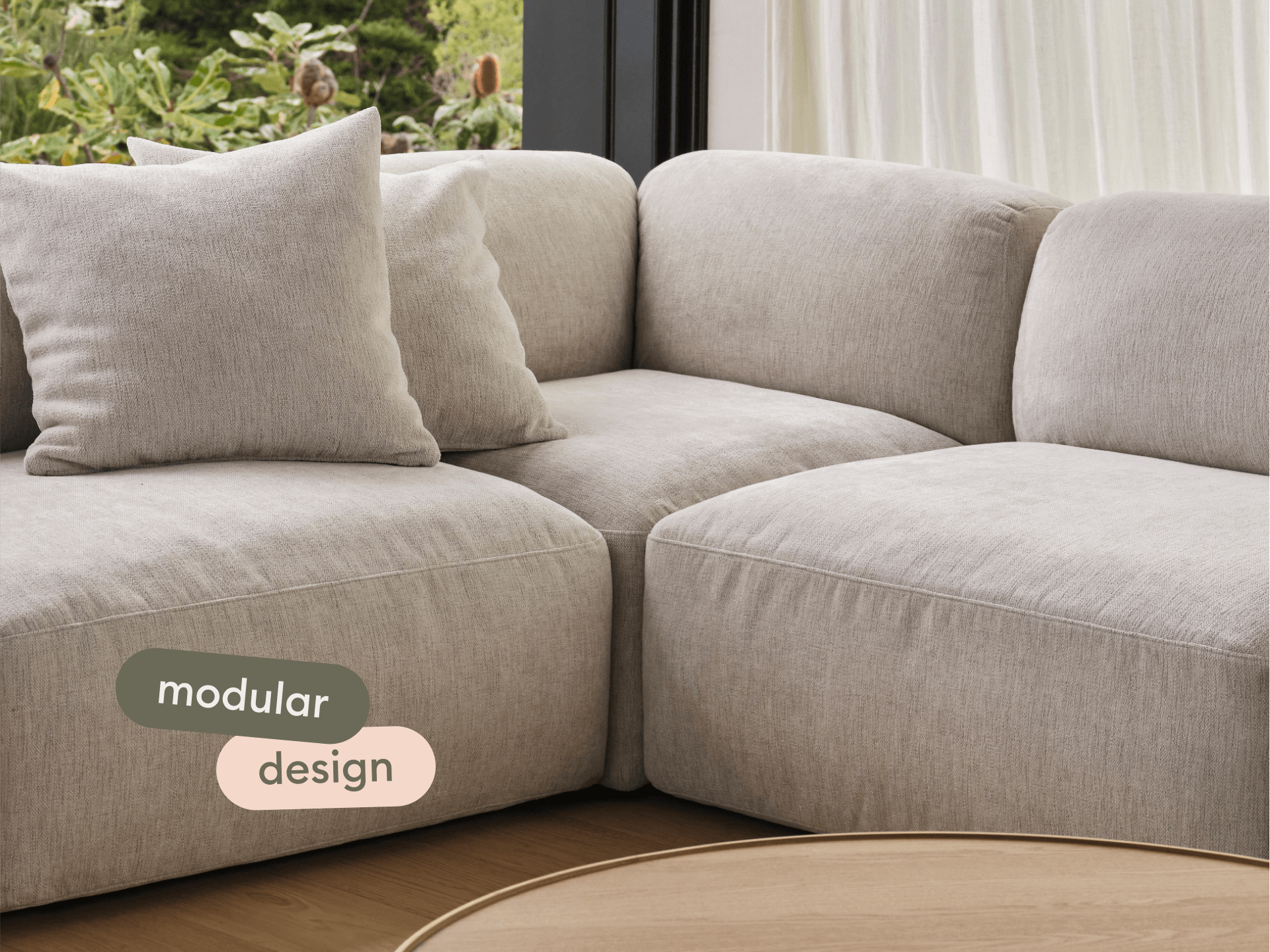 Luxurious beige linen modular sofa with plush cushions, elegantly placed in a bright living room. Complements light wood accents and outdoor views.