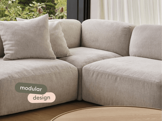 Luxurious beige linen modular sofa with plush cushions, elegantly placed in a bright living room. Complements light wood accents and outdoor views.