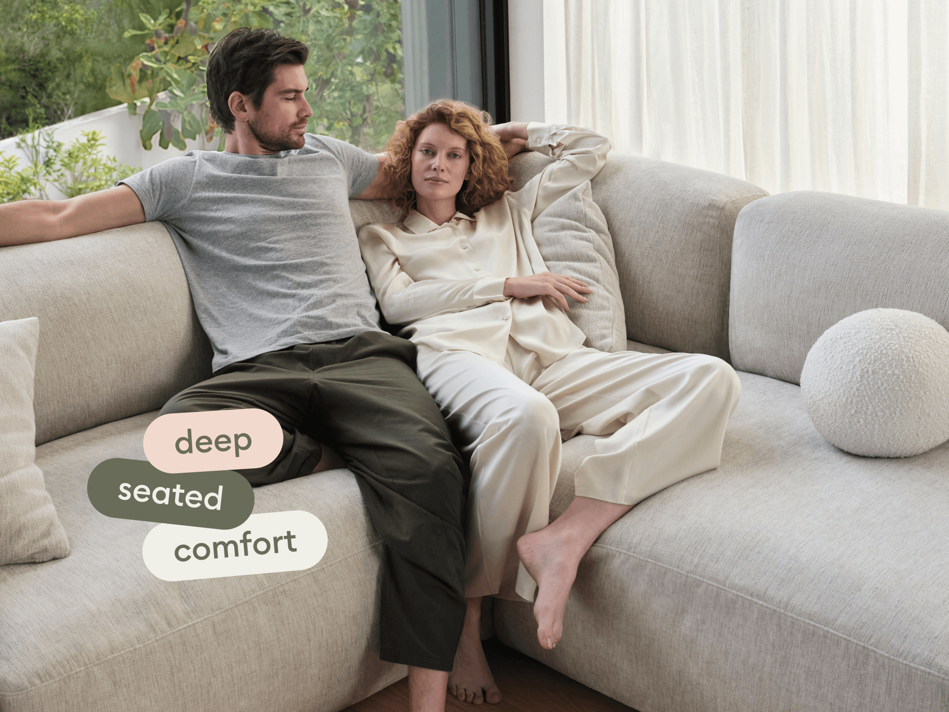 Luxurious modular sofa with deep seating in a soft beige fabric. Features plush cushions, perfect for a contemporary living room with large windows.