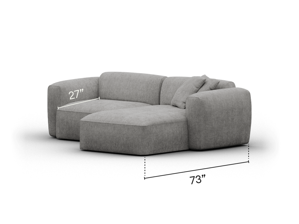Modern sectional sofa in soft grey upholstery, featuring plush cushions and a low-profile design. Perfect for sophisticated living spaces, measuring 73" in width.
