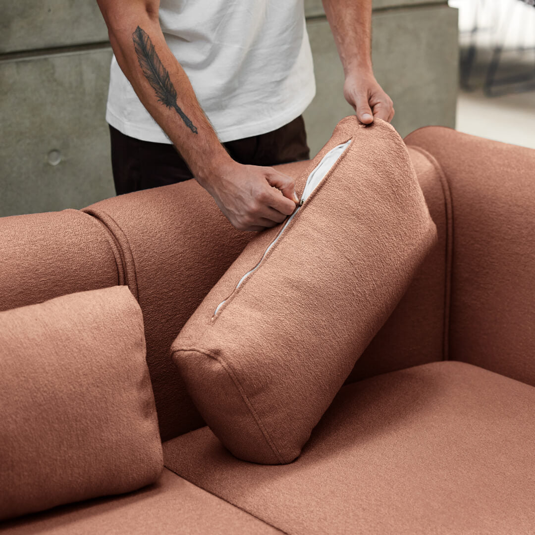 Close-up of a person easily removing the washable cover from a cushion of the Koala Bangalow Sofa, highlighting convenience and easy maintenance.
