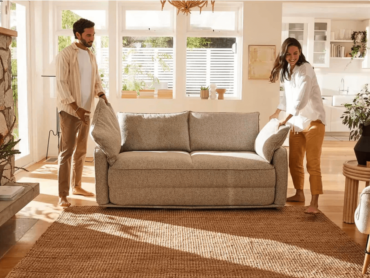 Luxurious grey linen sofa, plush and inviting, with removable cushions. Situated in a sunlit living room with wooden flooring and contemporary decor.