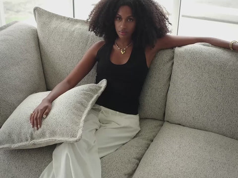 woman with multiple pillows on her on gray sofa