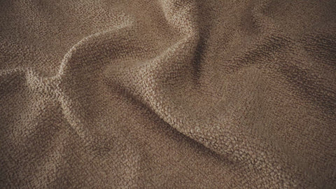 Close-up of luxurious beige boucle fabric, showcasing its textured woven finish. Ideal for high-end sofas and armchairs in modern, sophisticated settings.